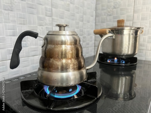 Obraz na plátne Close-up of a stainless steel gooseneck kettle boiling water on a gas stove, with a rustic worn finish and traditional kitchen setting