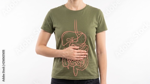 Woman wearing green t-shirt with anatomical digestive system print, hand on stomach area, health awareness, gastroenterology education, nutrition and gut health lifestyle concept