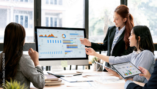 Asian Business Team Pointing Pens at Computer Screen Analyzing Dashboard in Office