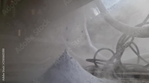 Cryogenic liquid nitrogen release with dry ice sublimation and dense white vapor near industrial machine parts