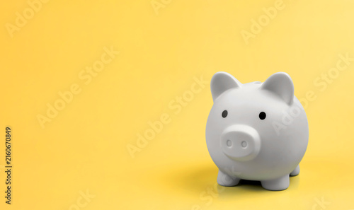 White minimalist piggy bank on vibrant yellow background with copy space. Concept of money saving, financial planning, investment, and wealth management.