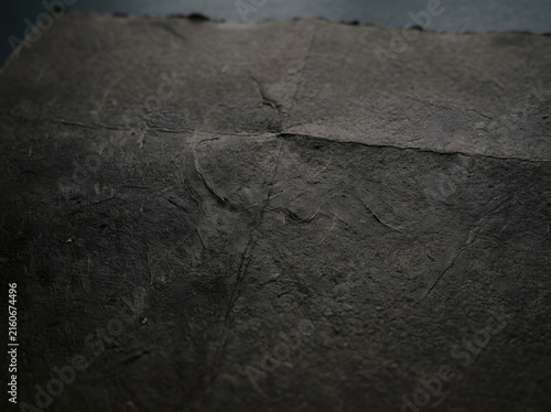 Close-up dark gray paper texture with deep creases and subtle shadows for design backgrounds