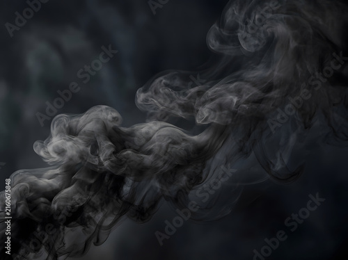 Dramatic swirling black smoke clouds in dark atmospheric abstract background for design