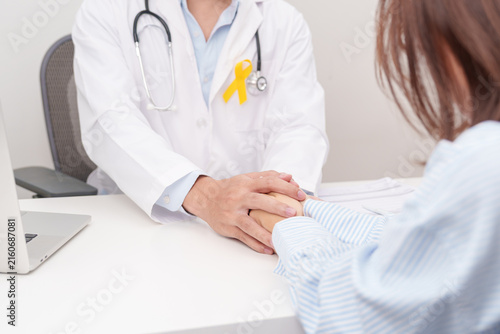 doctor holding patient hand to comfort and support with empathy for Yellow Ribbon concept of yellow September, Suicide prevention day, Childhood, July Sarcoma, bone and bladder cancer Awareness month