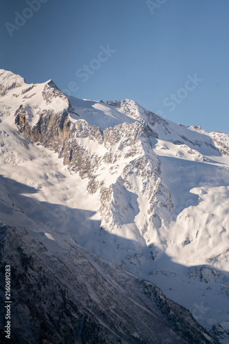 Foto Snow blankets the peaks of mountains under a clear blue sky in the late afternoo