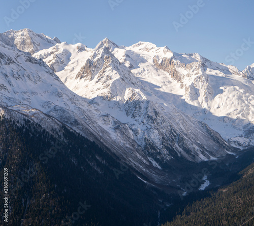 Photography Tall mountains are blanketed in snow with a clear blue sky above