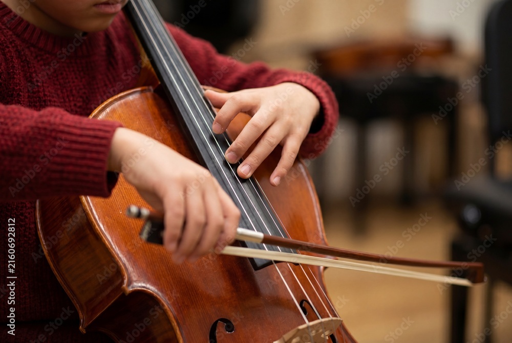 Fototapeta premium Young Student Playing Cello Focusing on Precise Finger Placement and Bow Technique