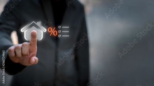Businessman using telephone and laptop with house interest rate icon. Concept of real estate tax, mortgage loan calculation, financial planning, and home property investment.