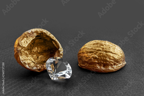 Diamond revealing from golden walnut shell on black background