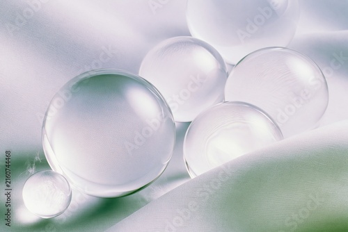 Clear glass spheres of varying sizes resting on soft draped fabric, featuring a serene and tactile mood for cosmetics and minimalist product staging with copy space