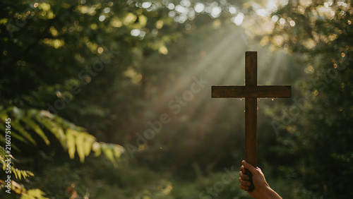 Hand Holding Wooden Cross Outdoors in Sunlight