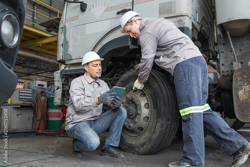Two mechanics inspecting truck tire condition during maintenance services.
