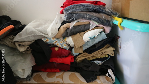 Quadro su tela Clothes creating a messy pile in a corner, depicting disorganization, storage is