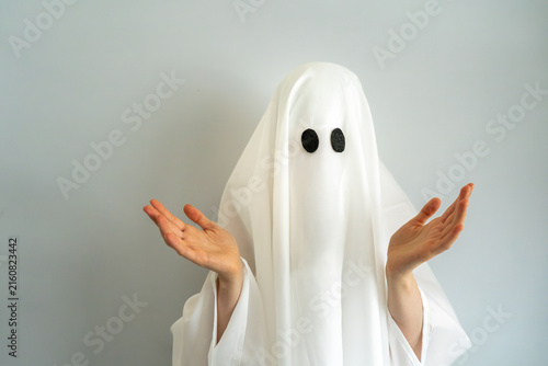 Halloween bedsheet ghost showing 'I don't know' hand gesture while standing on a simple background, copy space ghost, Halloween theme