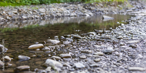 Canvastavla Closeup pebble strewn creek bed with shallow water and smooth stones for nature