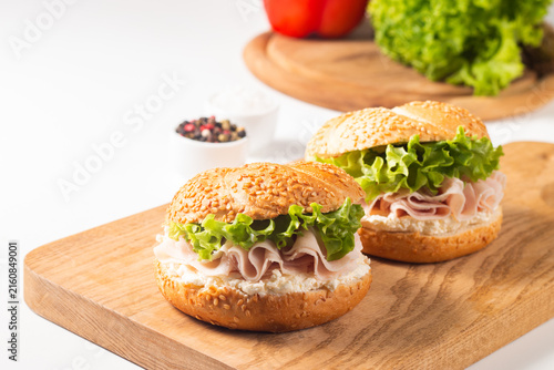 Sesame bagel sandwiches with turkey and chicken ham, cream cheese and fresh lettuce. Healthy food bun burger concept.