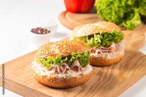 Sesame bagel sandwiches with turkey and chicken ham, cream cheese and fresh lettuce. Healthy food bun burger concept.
