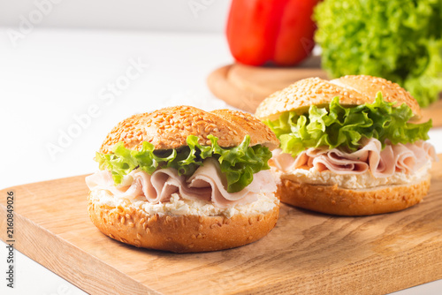Sesame bagel sandwiches with turkey and chicken ham, cream cheese and fresh lettuce. Healthy food bun burger concept.