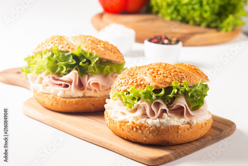 Sesame bagel sandwiches with turkey and chicken ham, cream cheese and fresh lettuce. Healthy food bun burger concept.