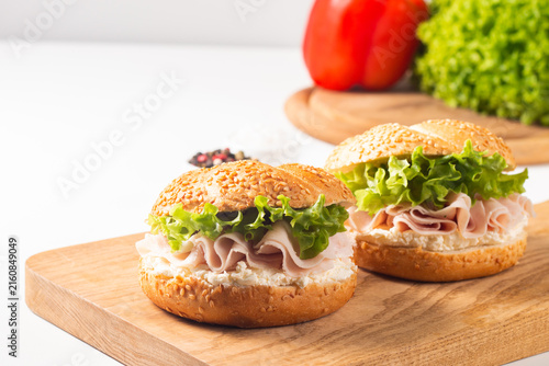Sesame bagel sandwiches with turkey and chicken ham, cream cheese and fresh lettuce. Healthy food bun burger concept.