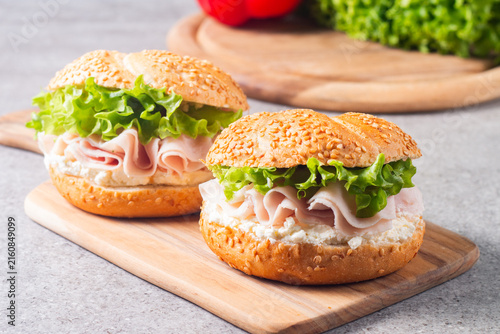 Sesame bagel sandwiches with turkey and chicken ham, cream cheese and fresh lettuce. Healthy food bun burger concept.