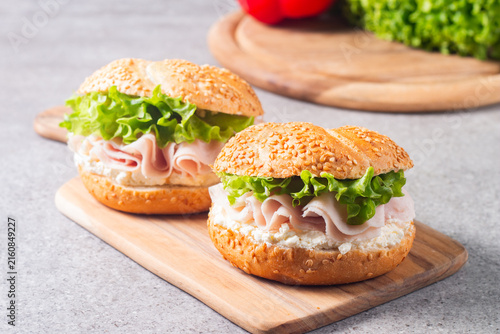 Sesame bagel sandwiches with turkey and chicken ham, cream cheese and fresh lettuce. Healthy food bun burger concept.