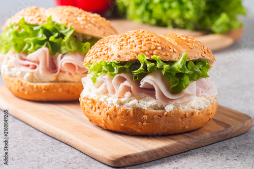 Sesame bagel sandwiches with turkey and chicken ham, cream cheese and fresh lettuce. Healthy food bun burger concept.