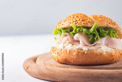 Sesame bagel sandwiches with turkey and chicken ham, cream cheese and fresh lettuce. Healthy food bun burger concept.