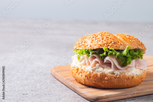 Sesame bagel sandwiches with turkey and chicken ham, cream cheese and fresh lettuce. Healthy food bun burger concept.