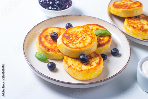 Golden cottage cheese pancakes with sour cream, blueberry jam and fresh berries. Healthy breakfast concept.