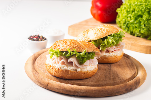 Sesame bagel sandwiches with turkey and chicken ham, cream cheese and fresh lettuce. Healthy food bun burger concept.