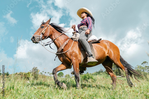 Canvastavla Cowgirl riding horse in green field under blue sky