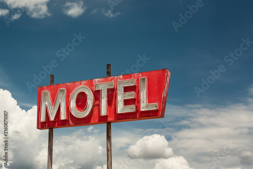 Vintage red mid-century neon motel sign, blue sky background, retro summer road trip and travel