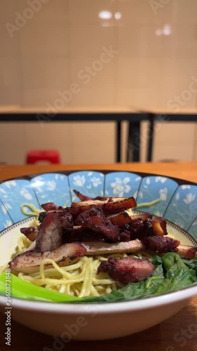Close up view of noodle on the bowl. chicken charsiu and mustard greens leaves. side, front. mie, bakmi. copy space, empty, free, negative, text, design. vertical, potrait. lights, bright