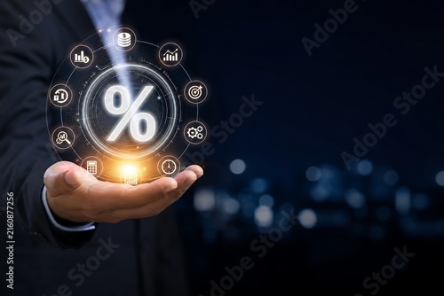 Businessman holding glowing percentage sign hologram with financial icons over city skyline
