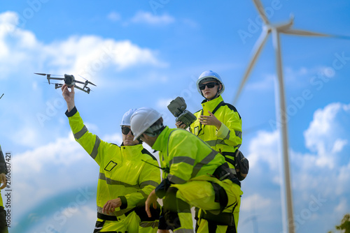 Foto A wind technician holds a quadcopter drone aloft in one hand as a bearded collea