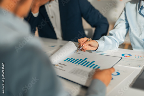 Business professionals collaborating, discussing monthly product sales reports with charts and graphs, planning strategy in a meeting