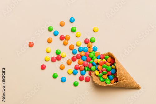 waffle cone full of assorted traditional candies falling out on colored background with copy space. Happy Holidays sale concept