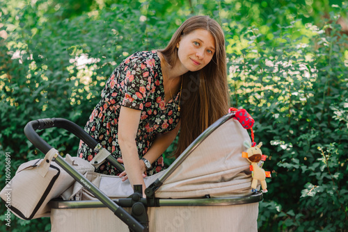 young mother with a stroller, out for a walk in summer.