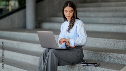 Young woman working on a laptop while sitting on outdoor stairs