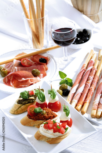Grissini with parma ham and olives and mozzarella with tomatoes, italian starters