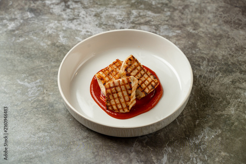 Grilled chicken served on a plate with sauce at a restaurant during dinner