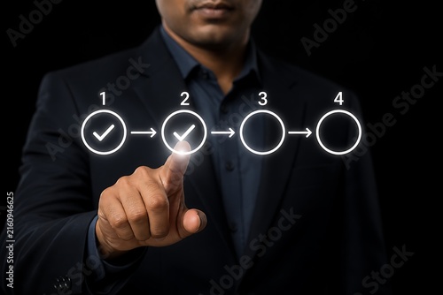 Businessman pointing at glowing four step process flowchart on dark background