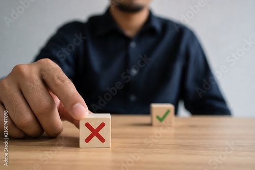 Hand placing wooden block with red x next to block with green checkmark on table
