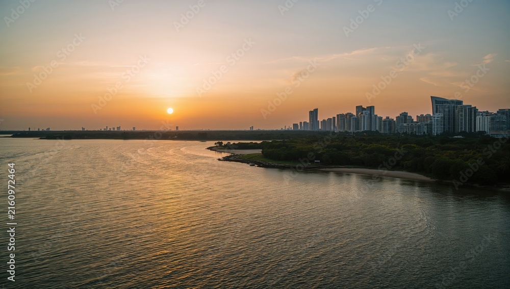 Fototapeta premium Urban Sunset Over Water with Reflections and City Skyline