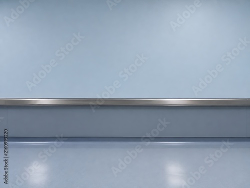 A clean and empty hospital hallway with light blue walls and a horizontal stainless steel handrail running along the center of the wall