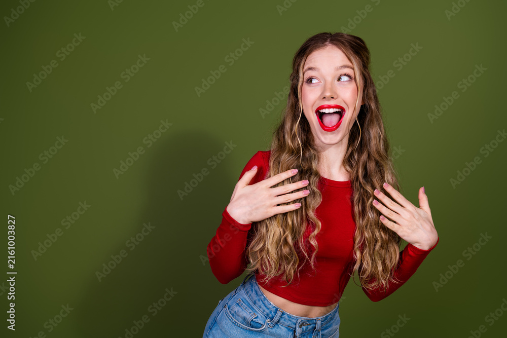 Naklejka premium Young woman in red top laughing with hands on chest against green studio background
