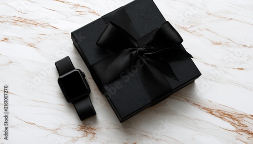 Elegant black gift box and smartwatch on marble surface