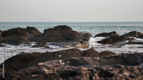 Powerful ocean waves crashing over dark, rugged rocks on the coastline, a dramatic slow motion scene symbolizing the urgent threat of climate change and rising sea levels on our planet