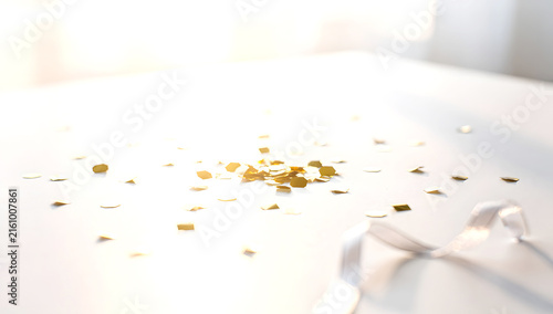 Scattered Gold Confetti and Curled Ribbon on Bright White Sunlit Surface